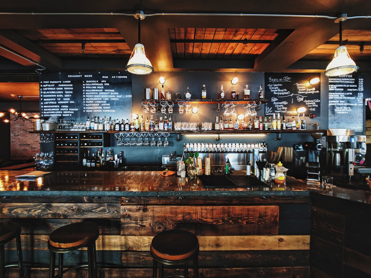 Warm wood bar with stools, taps, and hanging lights